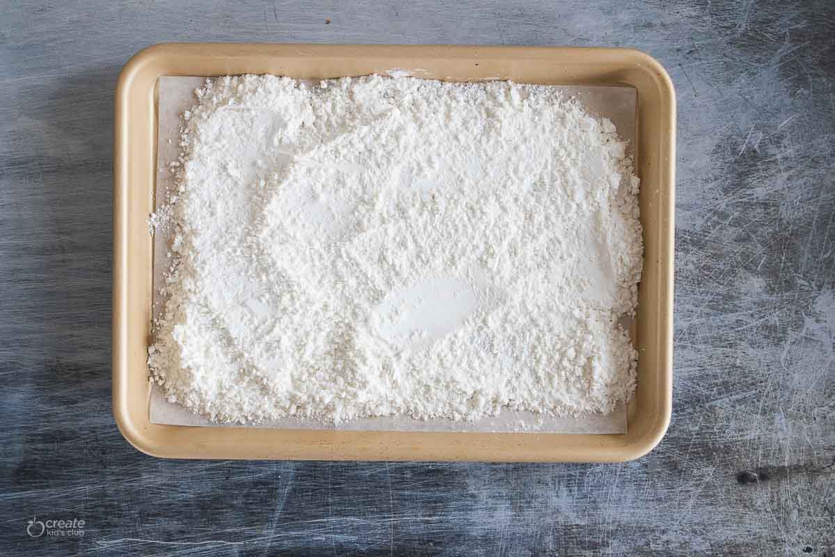 powdered sugar in a parchment lined baking pan