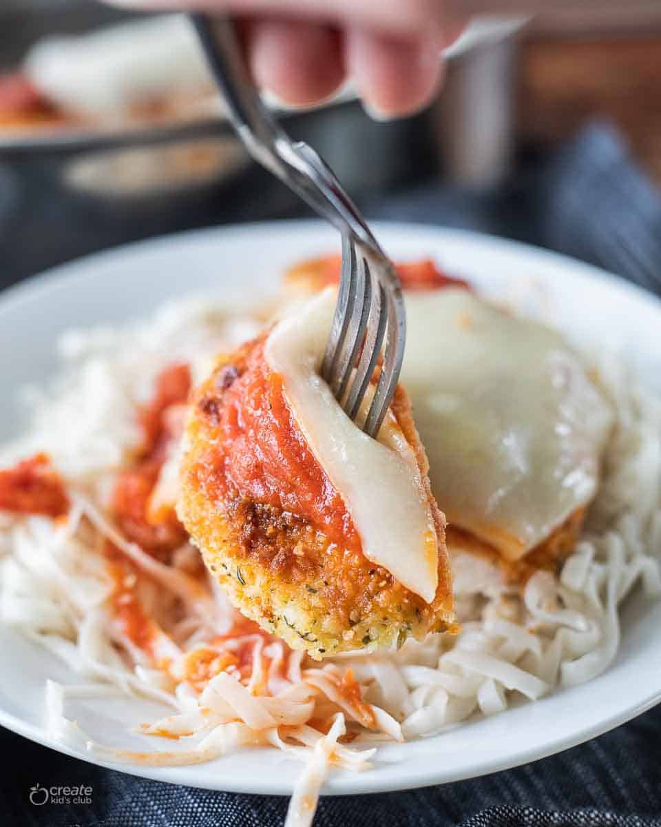 fork scooping a bite of gf chicken parmesan