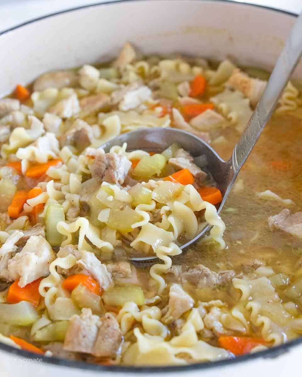 ladle scooping a serving of chicken noodle soup