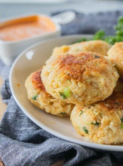 A plate stacked with cooked gluten free crab cakes.