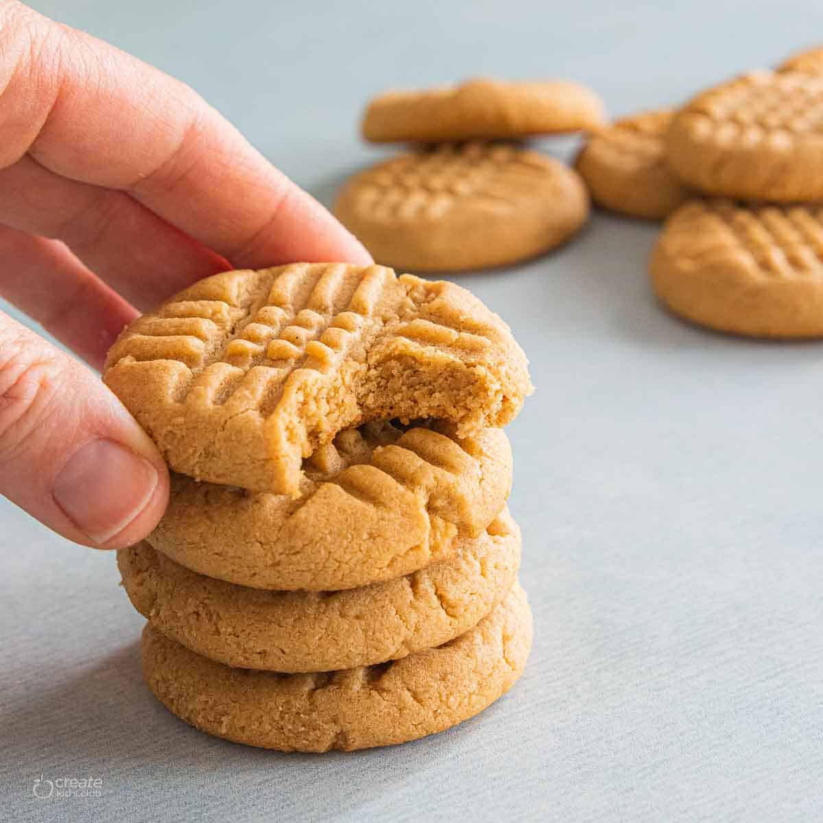 peanut butter cookies stacked with a hand grabbing the top cookie