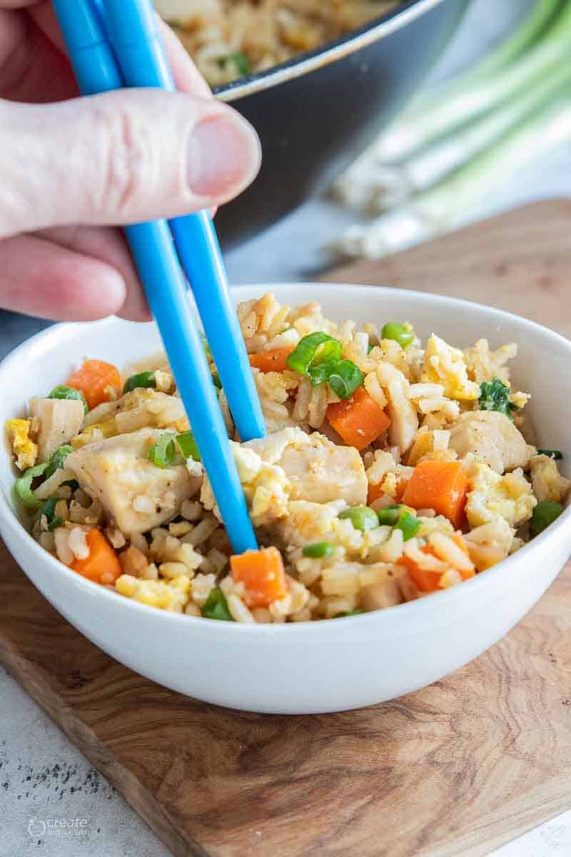 chopsticks in bowl filled with chicken fried rice