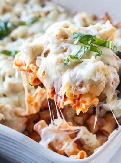 Gluten free chicken ziti baked with melted cheese being pulled with the scoop.