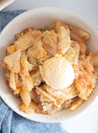 top view of apple cobbler in bowl topped with a scoop of ice cream