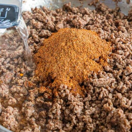 water being poured into pan with spices and browned beef