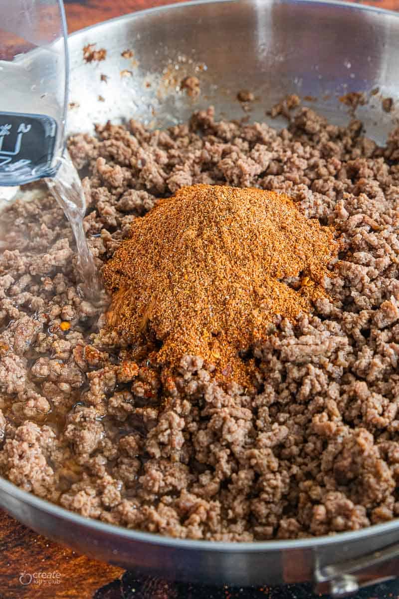 water being poured into pan with spices and browned beef