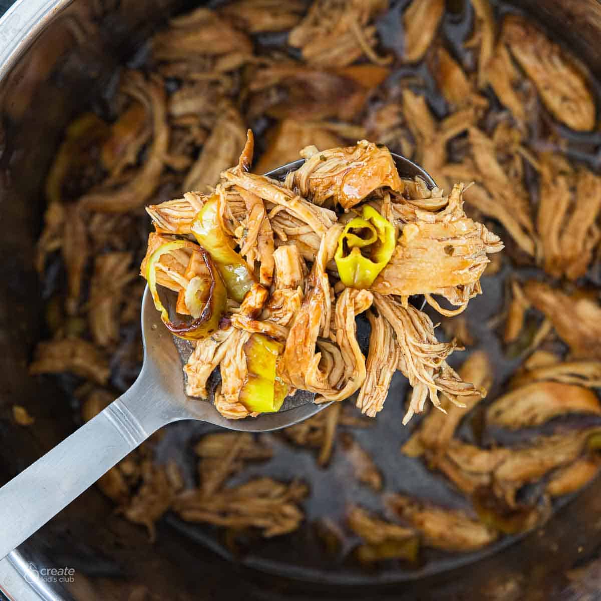 close up view of spoon ladling shredded chicken