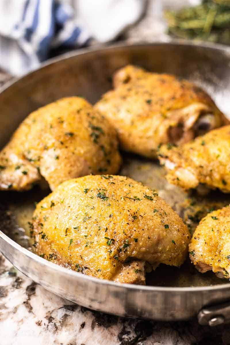 A close up of baked chicken thighs in a skillet.