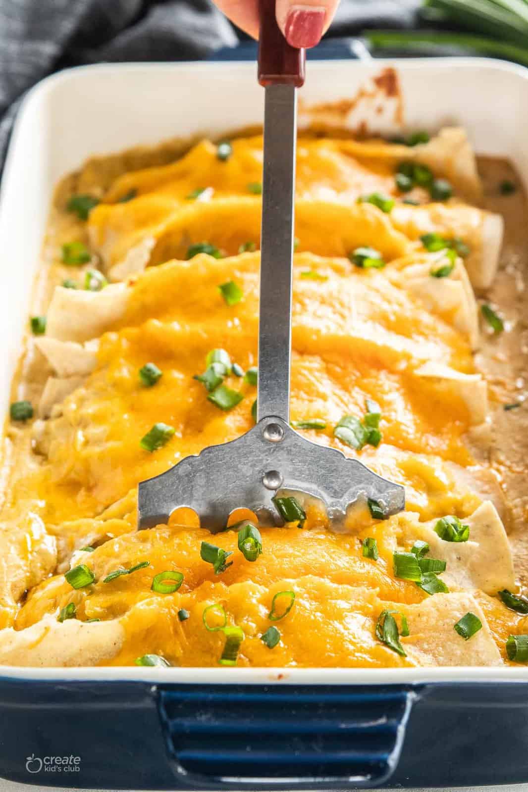 chicken enchiladas scooped from pan with spatula