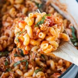 wooden spoon ladling parmesan pasta from pot