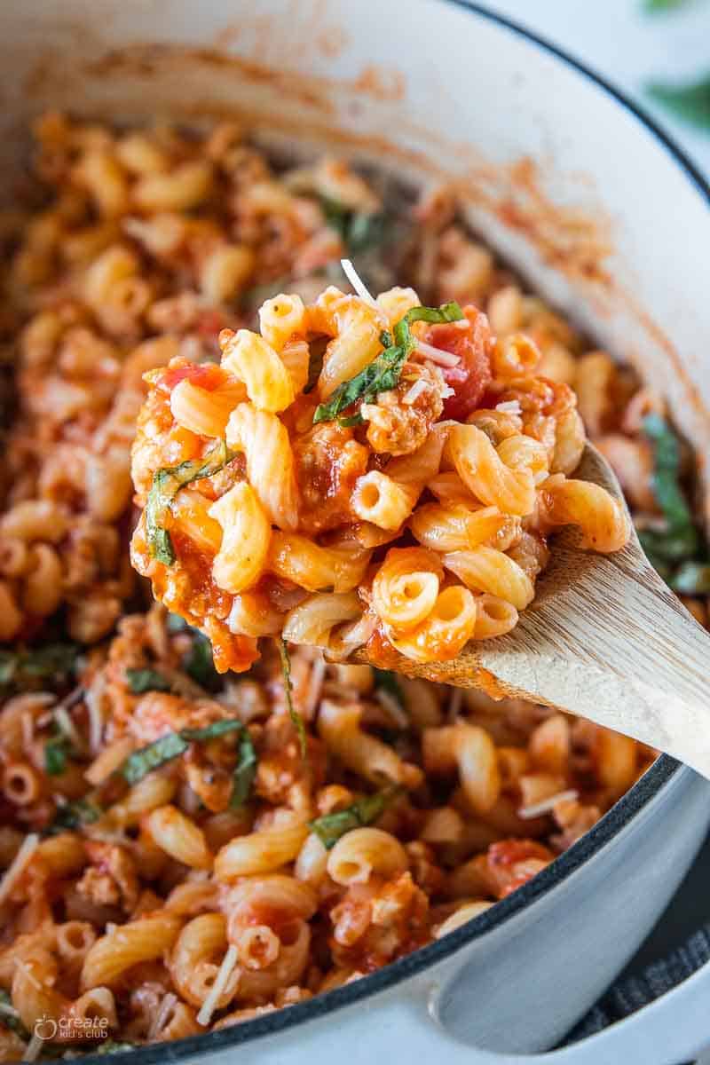 wooden spoon ladling parmesan pasta from pot