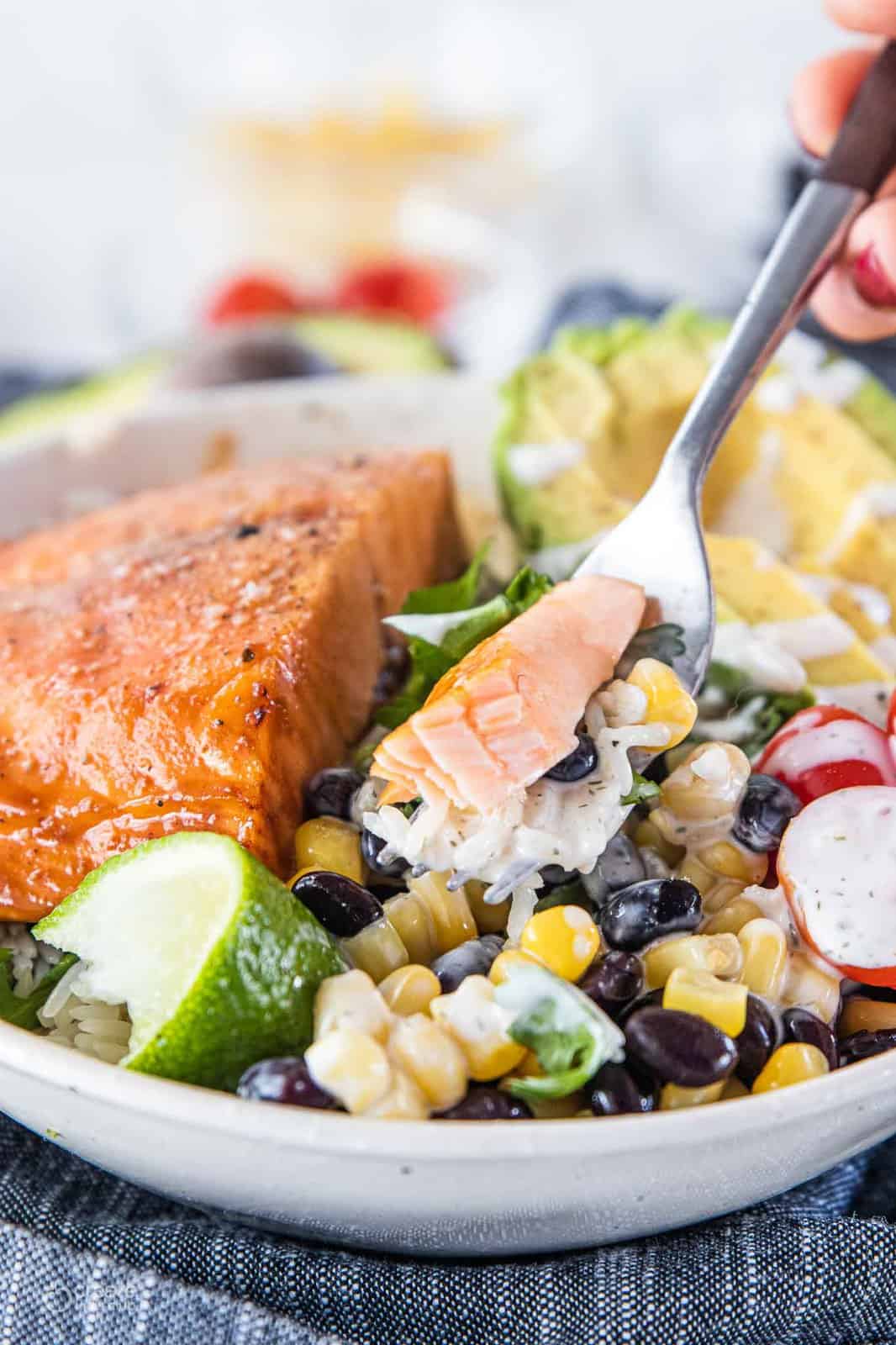 fork scooping bite of salmon buddha bowl
