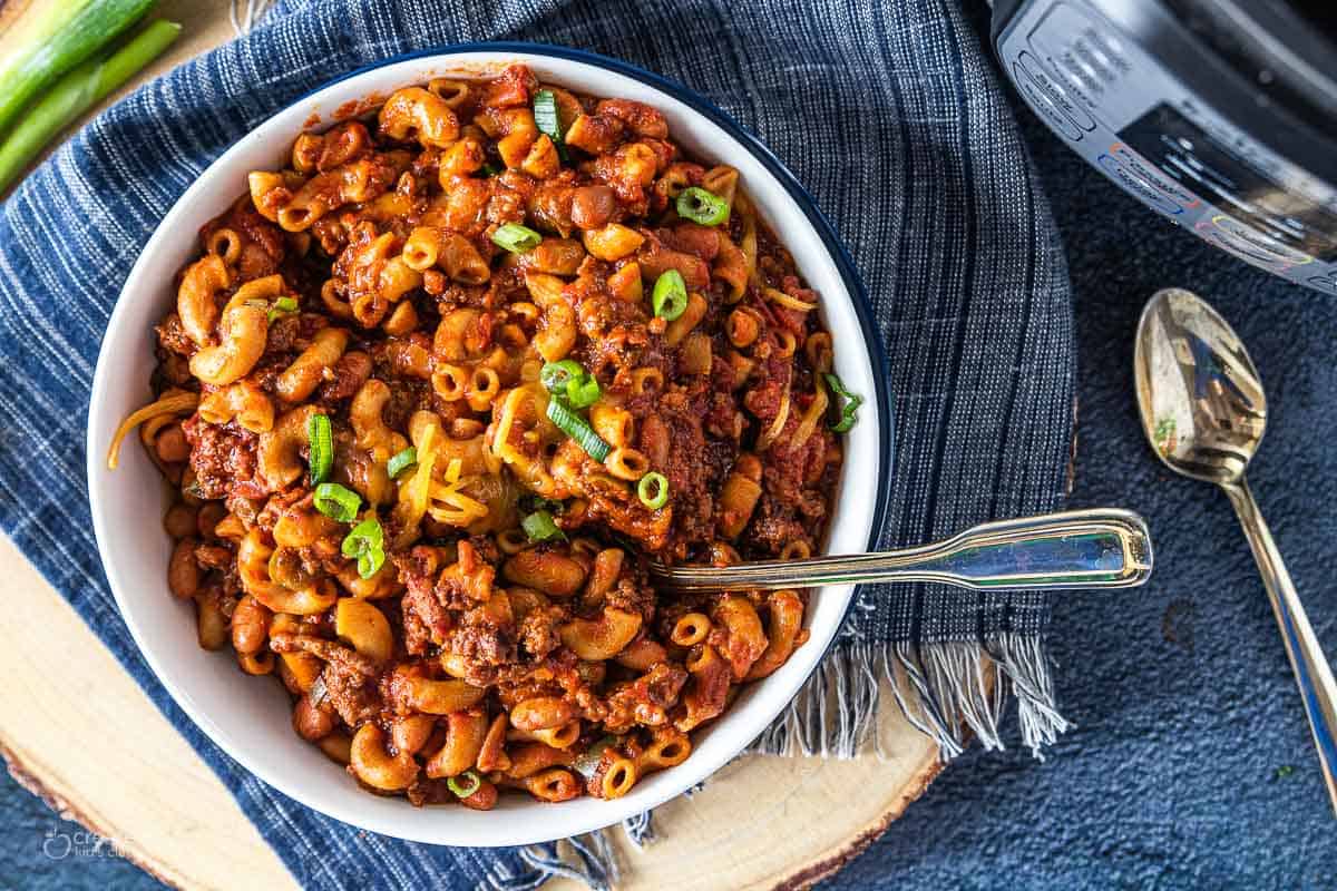 Chili Mac shown in a white bowl with an instant pot next to it.