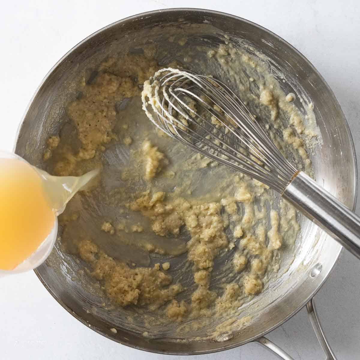 broth slowly whisked into flour and garlic mixture