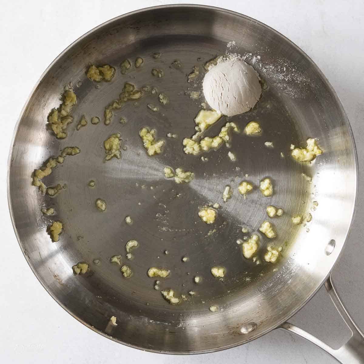 scoop of flour added to pan with minced garlic