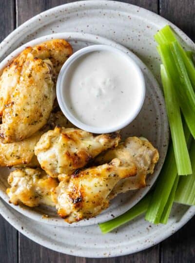 air fryer chicken wings on plate with raw celery and dipping sauce