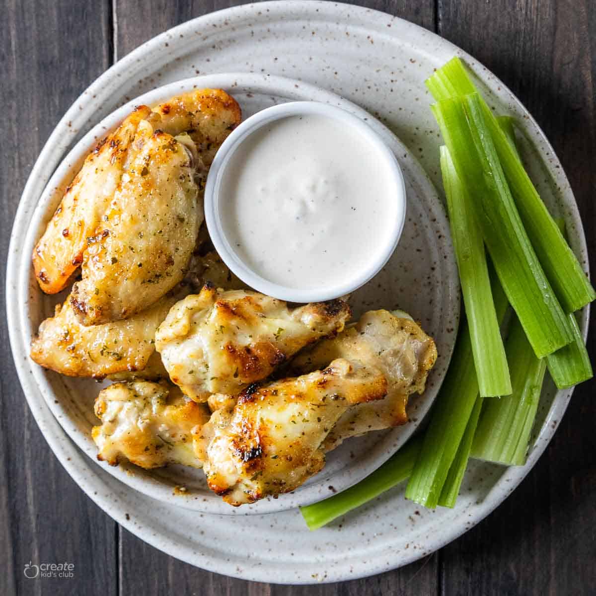 air fryer chicken wings on plate with raw celery and dipping sauce