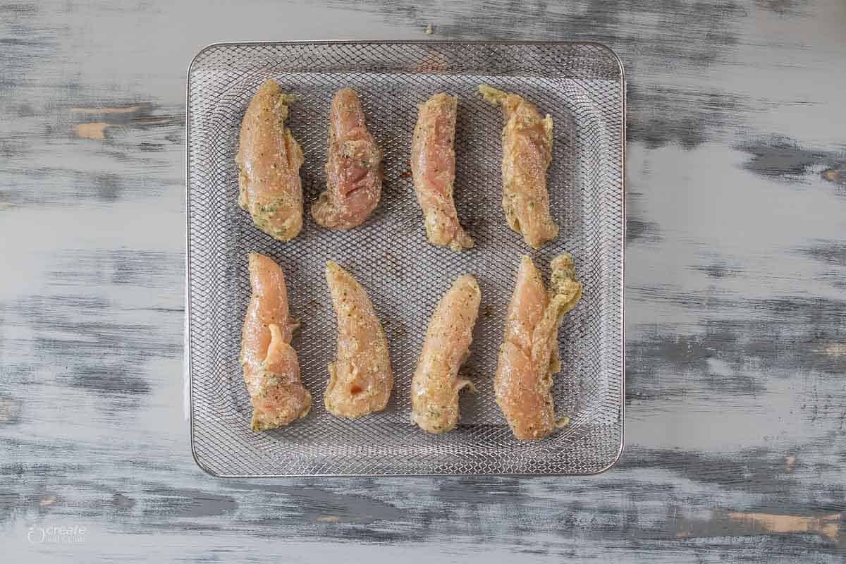 raw chicken tenders on air fryer tray