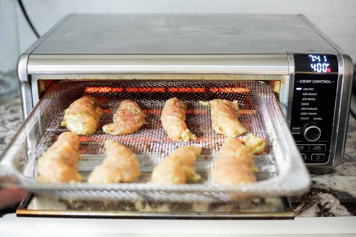 raw chicken tenders placed into air fryer