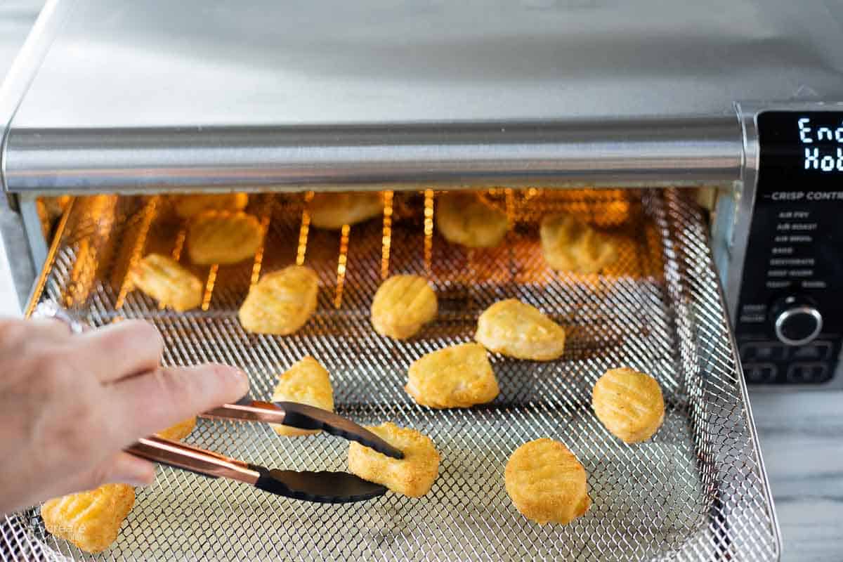 tongs picking up air fried chicken nugget