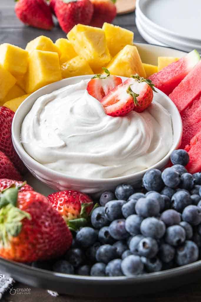 bowl of fruit dip with cool whip on platter with fruit