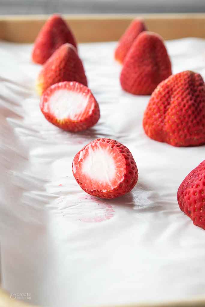 frozen strawberries on parchment lined baking sheet