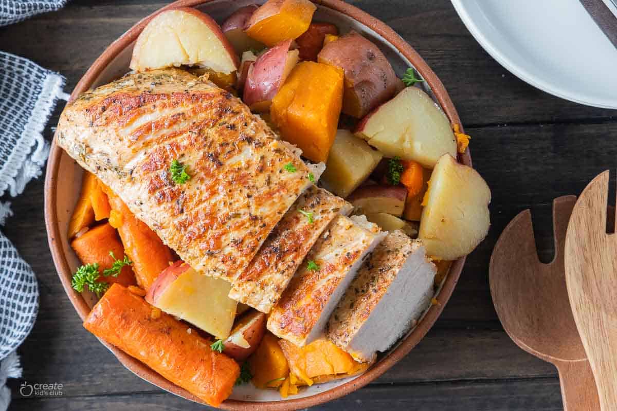 sliced pork roast with potatoes in serving bowl