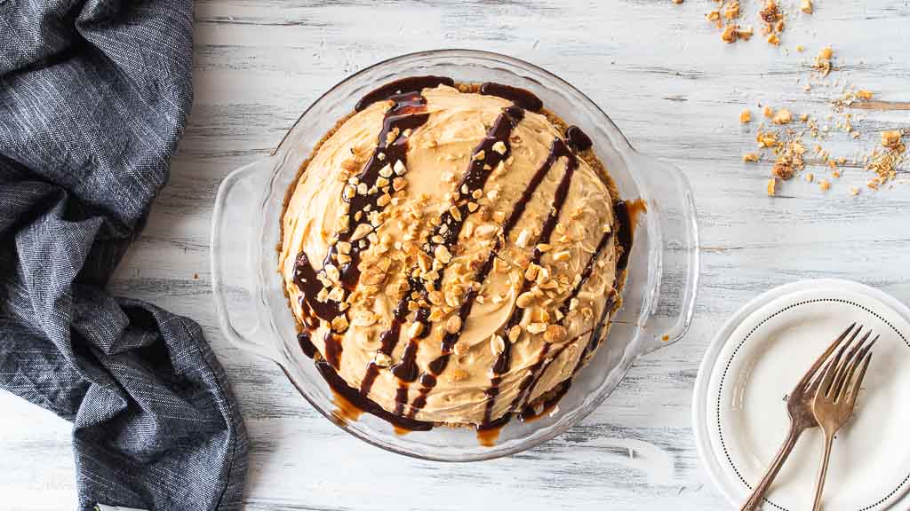 peanut butter pie drizzled with chocolate syrup and topped with nuts