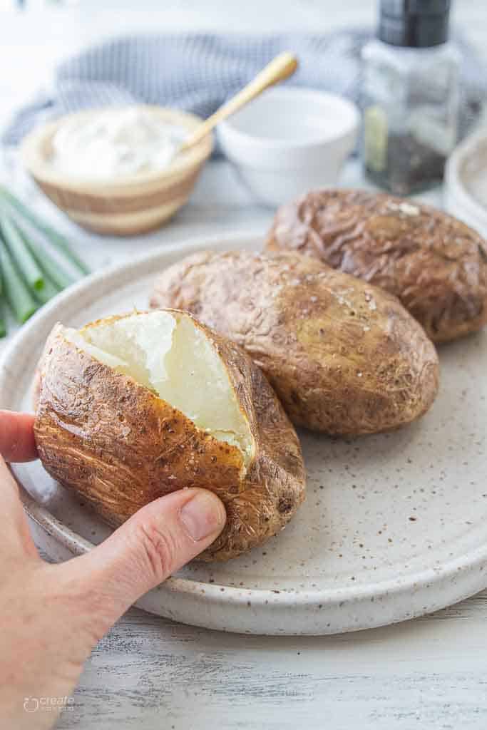 hand opening baked potato