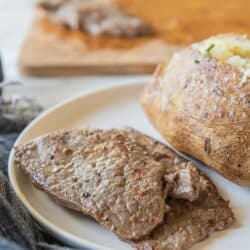 thin steak on plate with baked potato