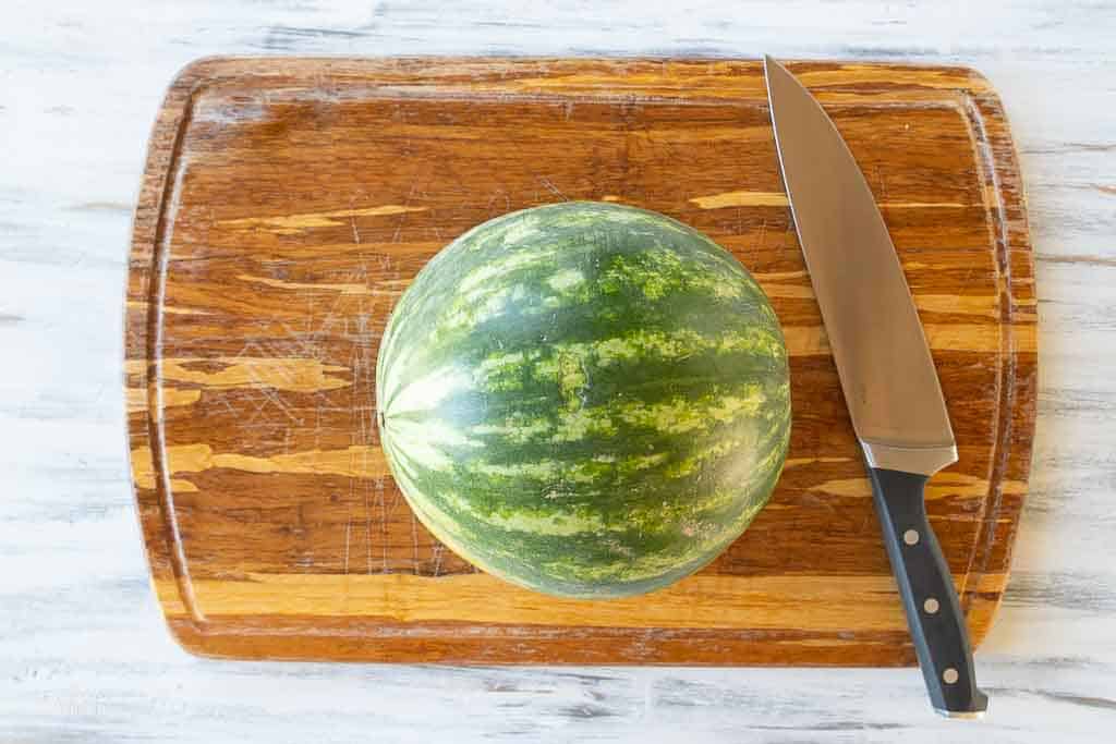 whole watermelon on cutting board with knife