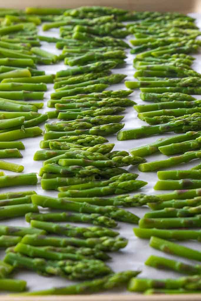 frozen asparagus stems on parchment lined baking sheet