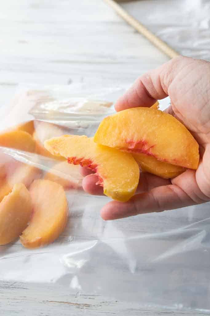 hand holding frozen peach slices