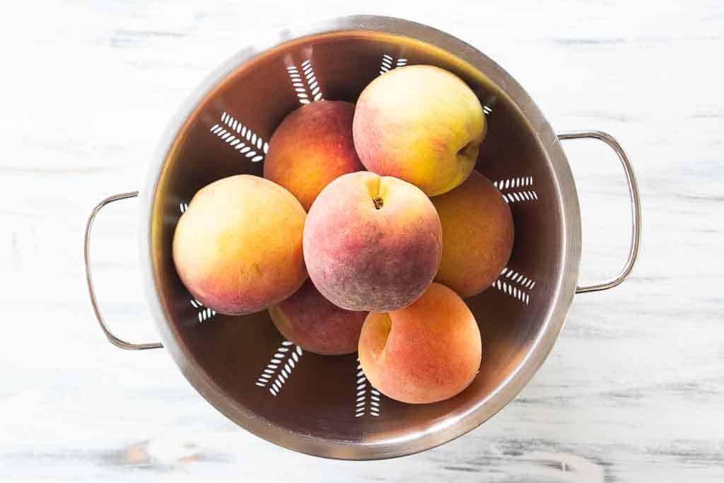 top view of whole peaches in a colander