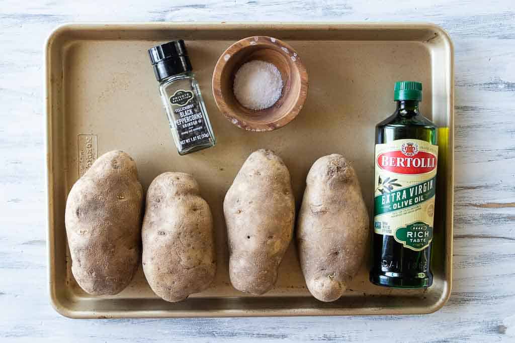 ingredients for microwaved baked potatoes on a sheet pan