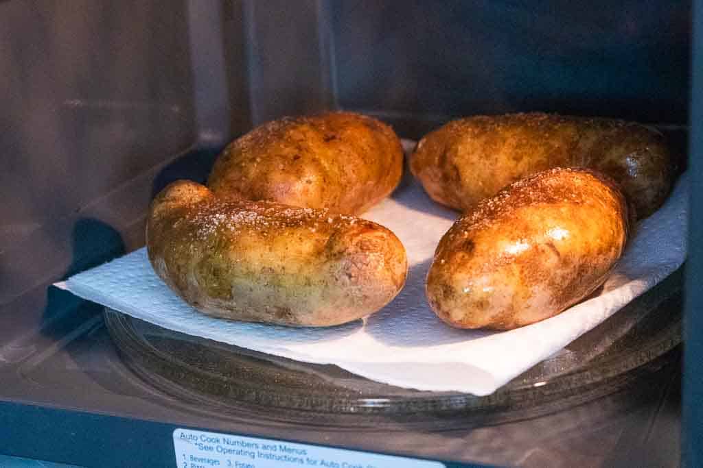 four baked potatoes in a microwave