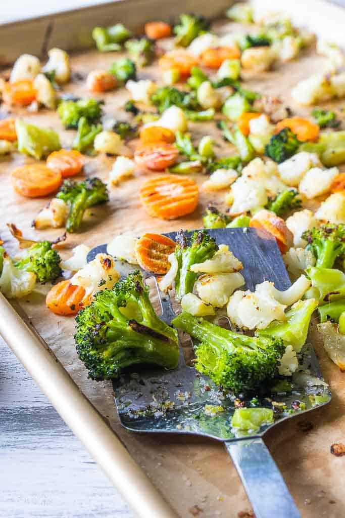spatula scooping frozen veggies on sheet pan