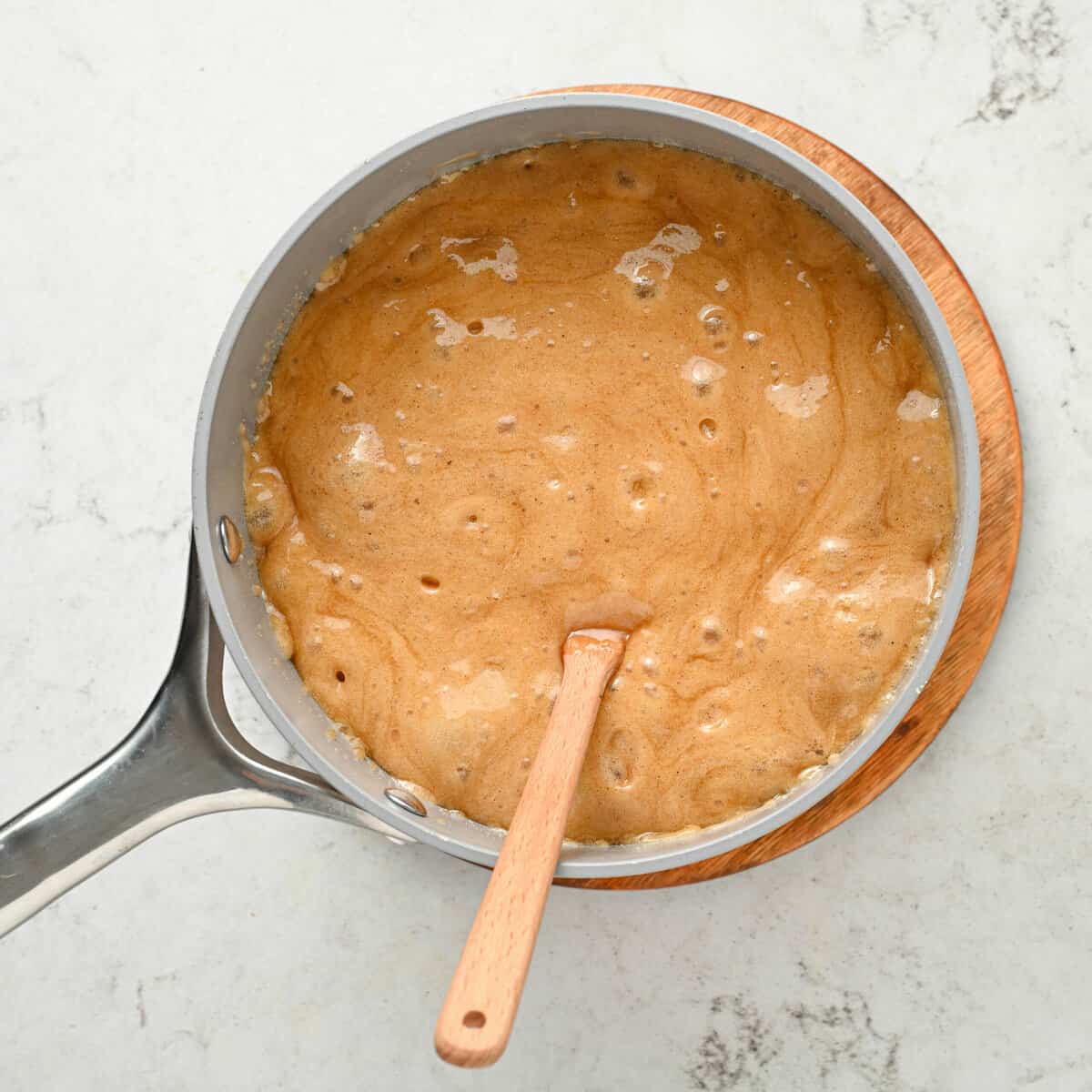 wooden spoon in pot of boiling caramel sauce