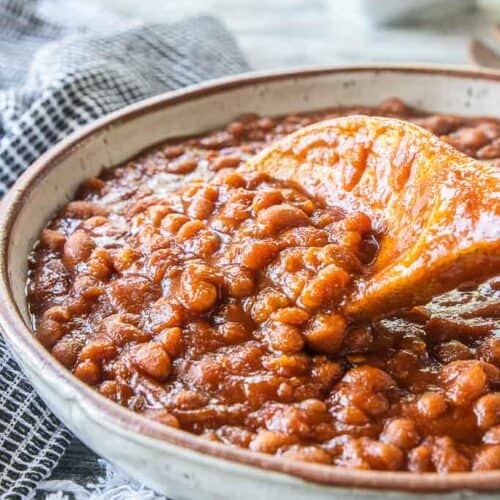 homemade baked beans in a serving bowl with wooden spoon