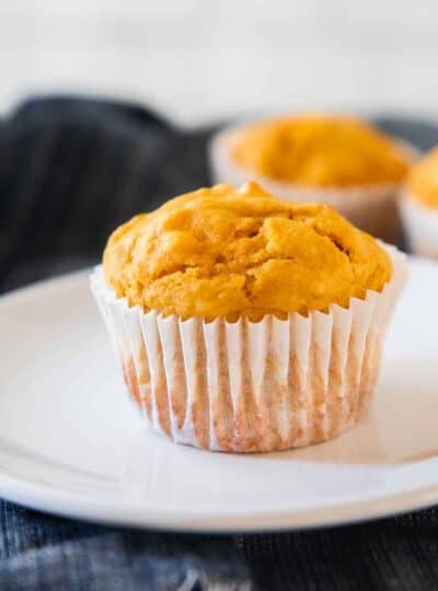 A pumpkin muffin up close on a white plate.