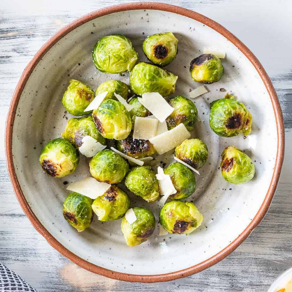 roasted brussels sprouts in a bowl topped with grated parmesan cheese