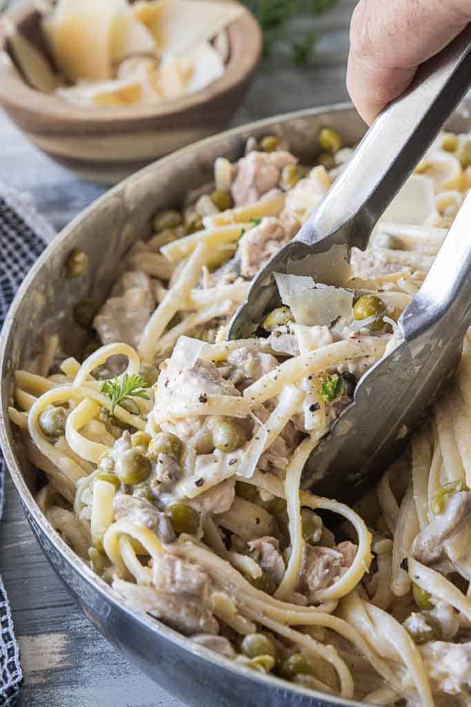 tongs tossing together gluten free salmon pasta recipe