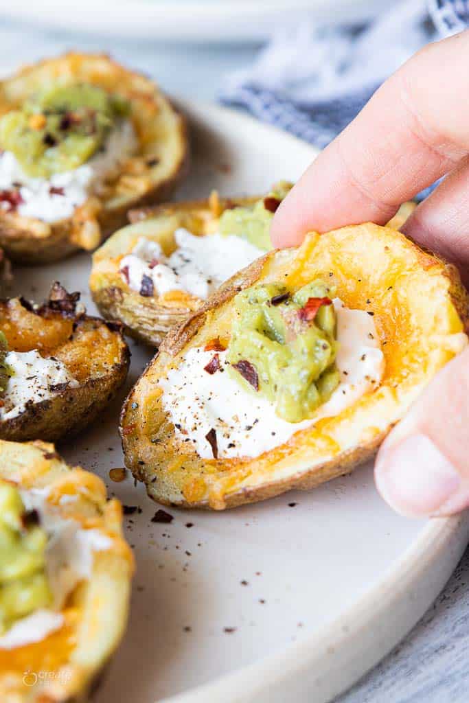 hand holding air fryer potato skin with toppings