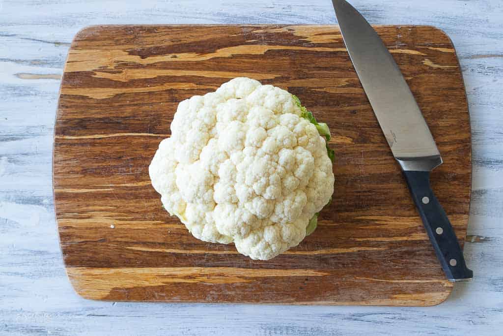 whole cauliflower on cutting board with knife