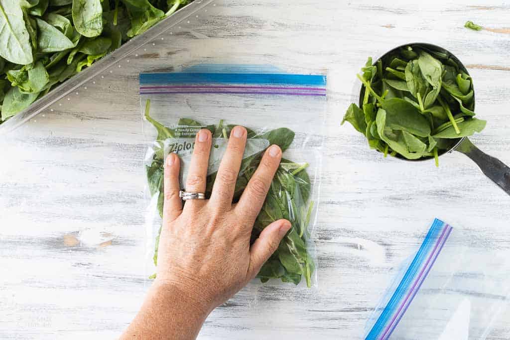 hand pressing spinach in a Ziplock bag