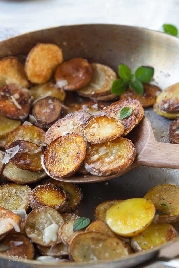 wooden spoon scooping sliced potatoes