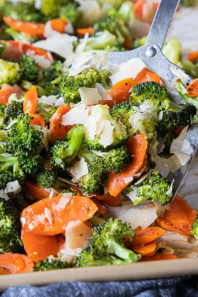 spatula scooping roasted broccoli and carrots from pan