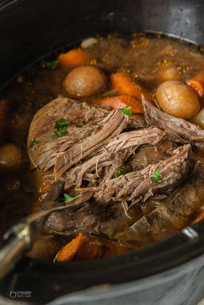 roast being shredded in crockpot