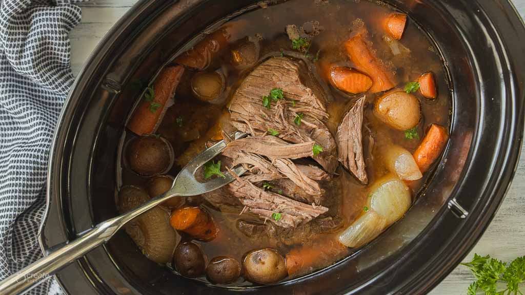 roast being shredded in crockpot