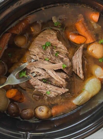 roast being shredded in crockpot